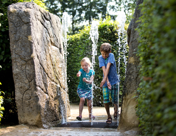 Kinderen rennen door fontein bij het Drielandenpunt doolhof