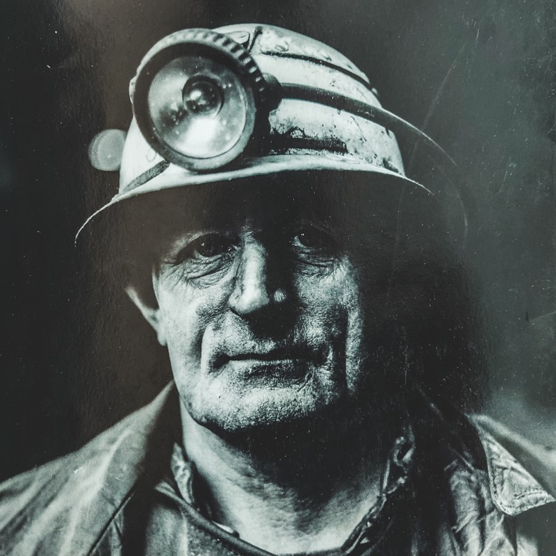 Zwart wit foto van Mijnwerker met helm en hoofdlamp op.