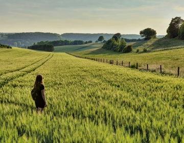 Vrouw staat in een veld en kijkt naar het uitzicht